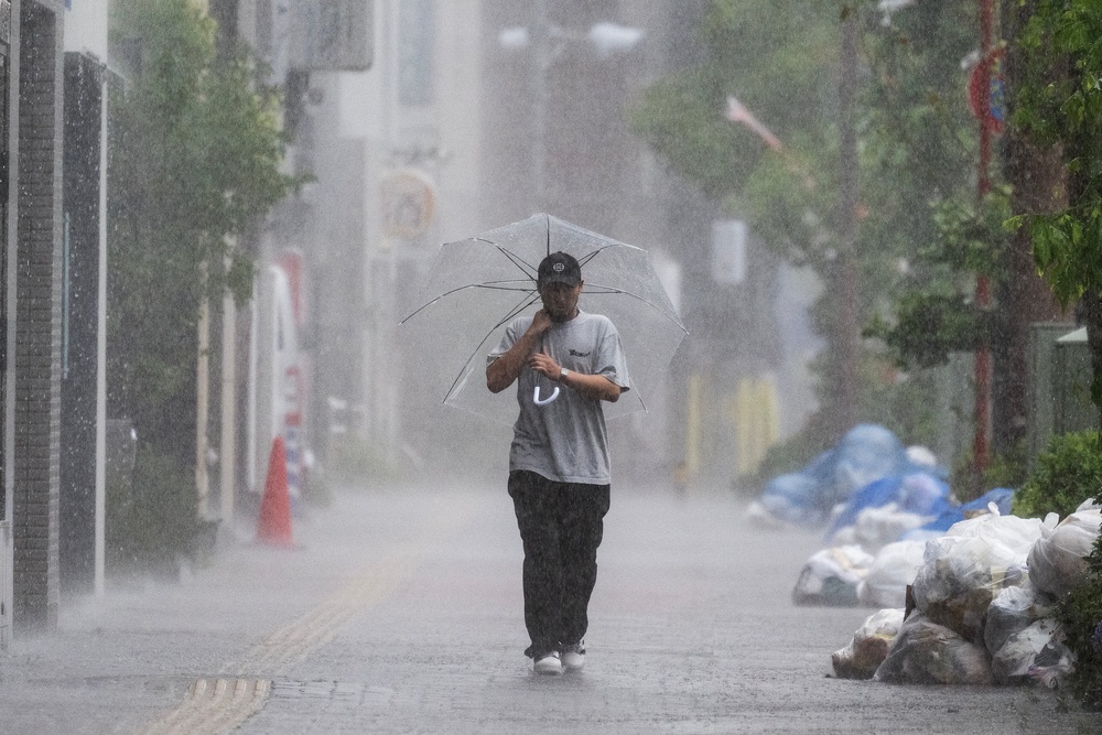 A man walks down a sidewalk in heavy rain brought by severe tropical storm Jangmi in Tokyo on 3 June 2026 (AFP/Getty)