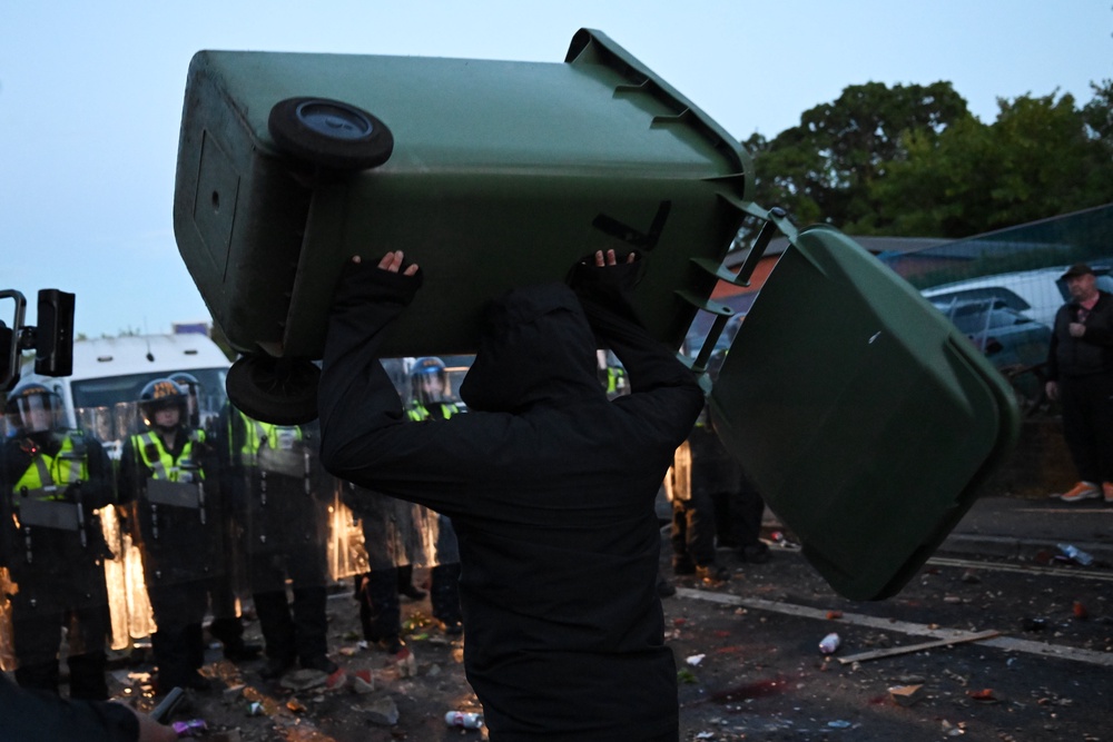 A man prepares to throw a wheelie bin at police officers during violence in Southampton on Tuesday night (Getty)