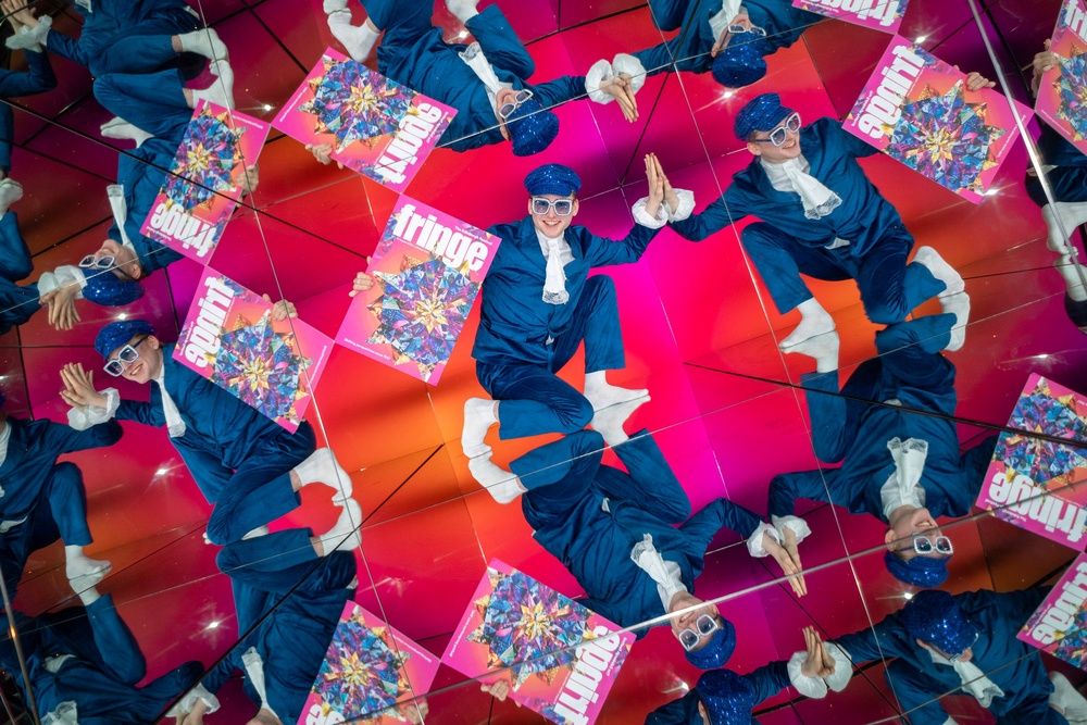 Performer Fintan McCarney poses with an oversized cut-out of the Edinburgh Fringe festival programme within Camera Obscura's Giant Kaleidoscope in Edinburgh (PA)