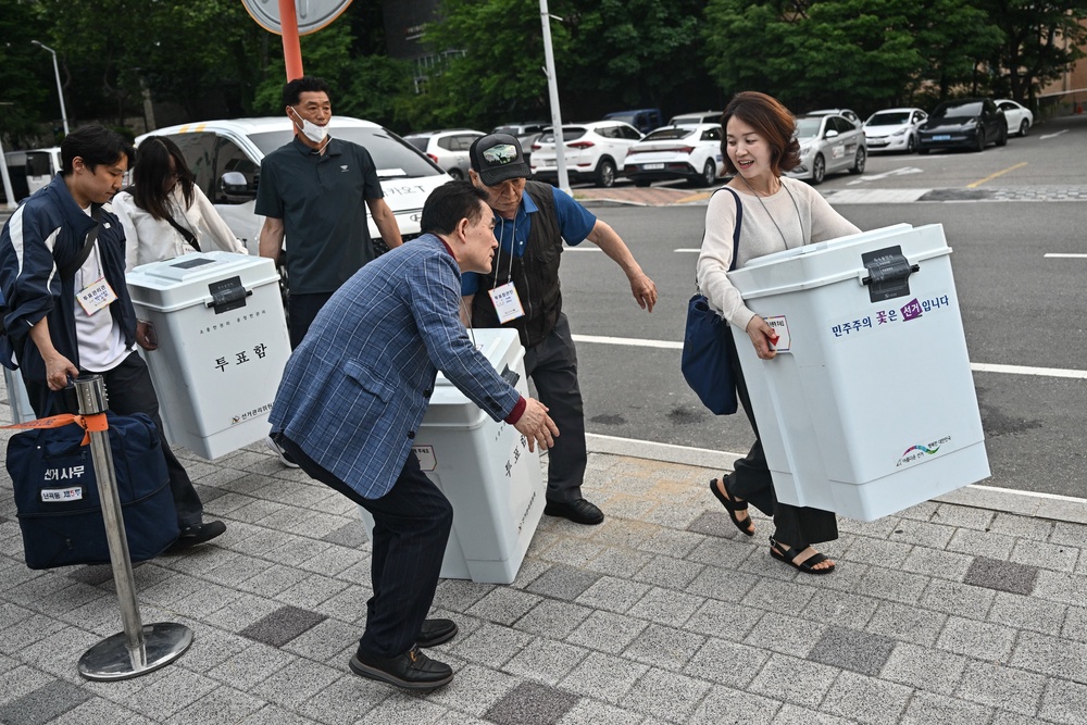 Election officials carry ballot boxes outside a counting station for local elections in Seoul on 3 June 2026 (AFP/Getty)