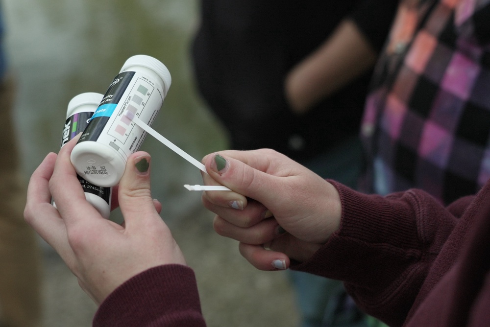 A Drake University student holds a phosphate test strip after sampling water from a stream (AP Photo/Brittany Peterson)