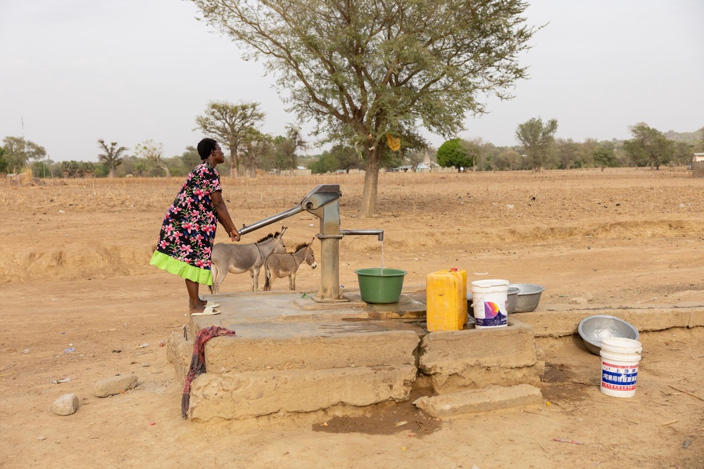 Sophia, 31 and eight-months pregnant, collecting water at a hand-pump borehole in Atampiisi (Basile Ouedraogo/WaterAid)
