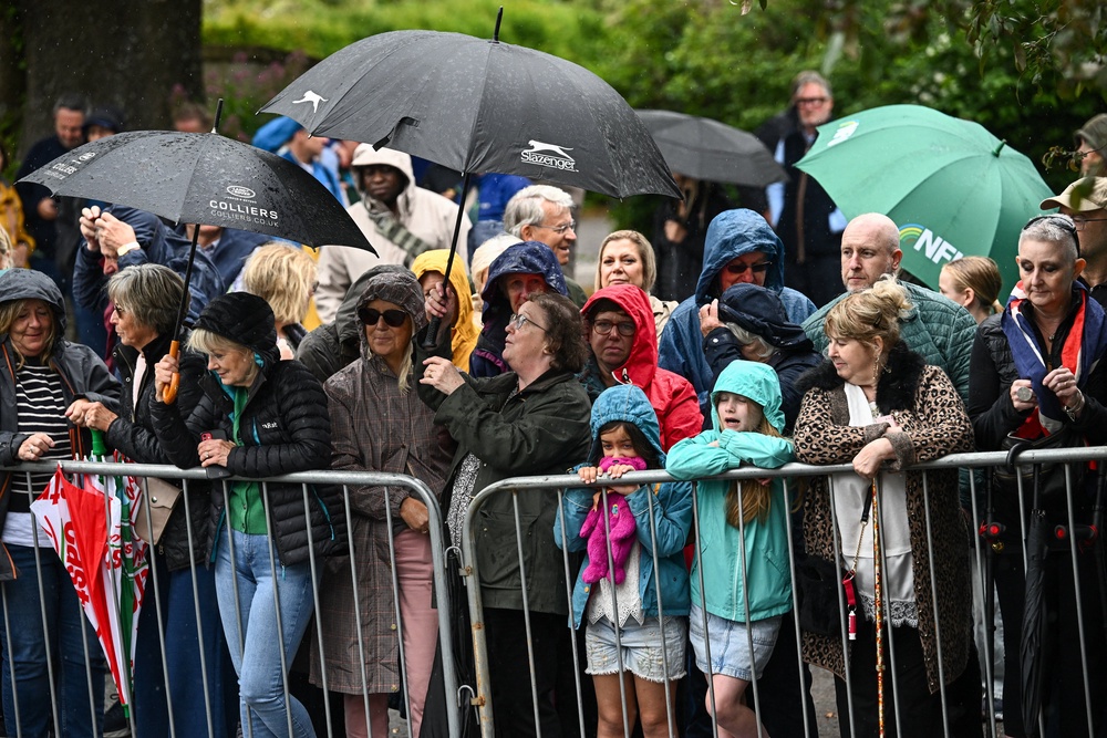 People use umbrellas to shield from the rain as they gather outside All Saints' Church (Reuters)