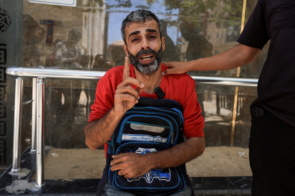 Palestinian father Youssef Salman mourns as he carries the school bag of his eight-year-old son Jad, who was killed in an Israeli strike on the Jabalia refugee camp (Reuters)