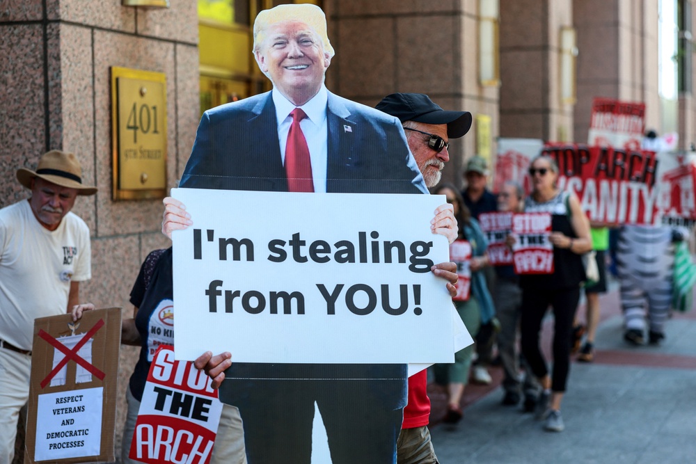 A protester holds a cutout of President Donald Trump during a demonstration against the president’s proposed triumphal arch before the public comment period of a National Capitol Planning Commission meeting in Washington on June 4, 2026 (Reuters)