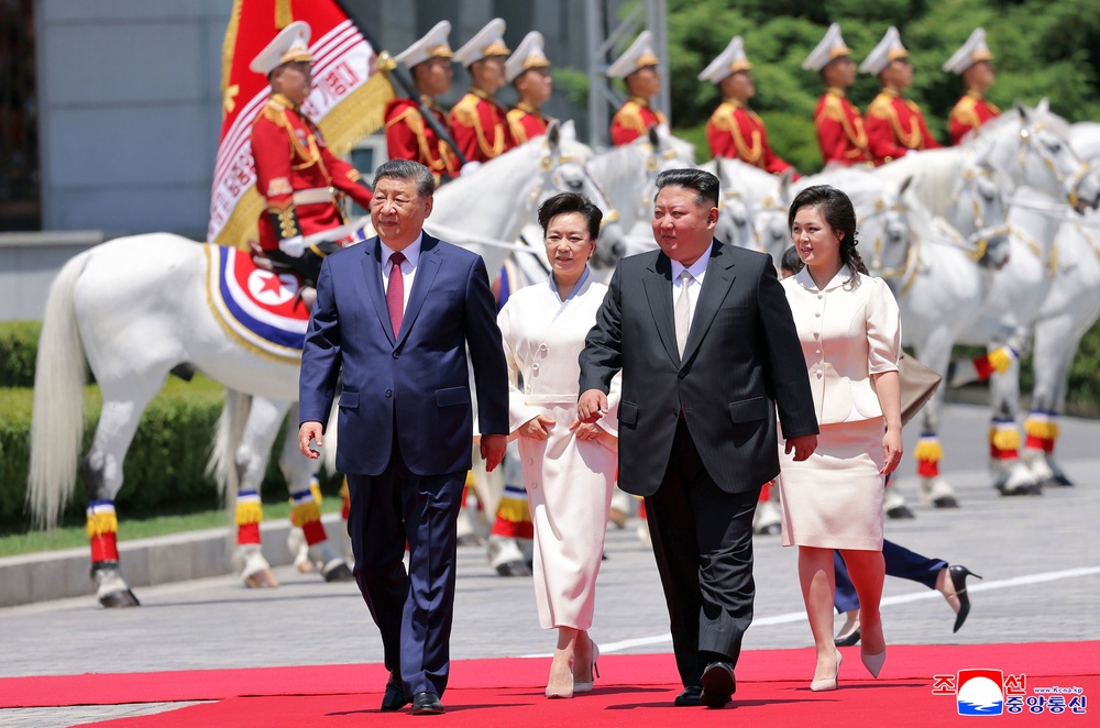 Chinese president Xi Jinping, left, and his wife Peng Liyuan, second left, accompanied by North Korean leader Kim Jong Un, second right, and his wife his wife Ri Sol Ju, attend a welcome ceremony in Pyongyang, Monday (AP)