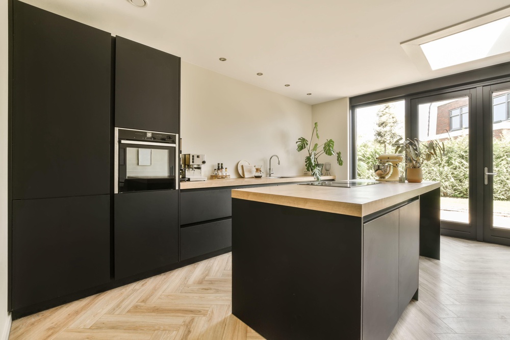 A modern kitchen with black cabinetry and wood flooring (Alamy/PA)