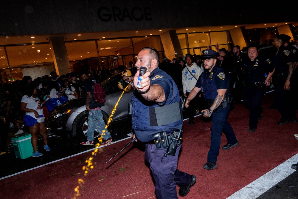 An NYPD officer uses pepper spray as New York Knicks fans clash with officers (Getty)