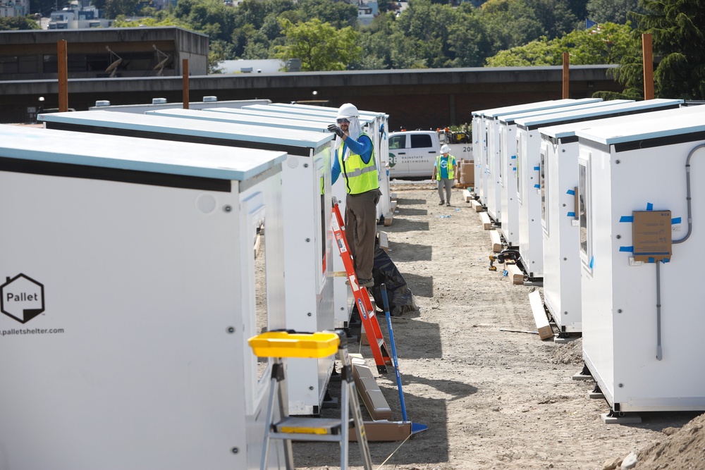 A worker inspects the top of a Pallet Shelter unit being installed in Seattle. The single-bed units, made of composite panels, are part of Seattle Mayor Katie Wilson's plan to expand shelter for the city's homeless (AP Photo/Manuel Valdes)