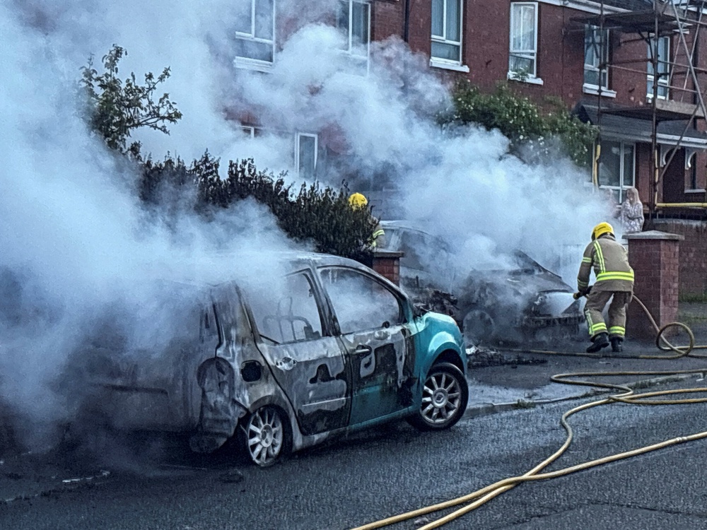 Firefighters work to extinguish a fire in three cars parked on the street at Tigers Bay (Reuters)