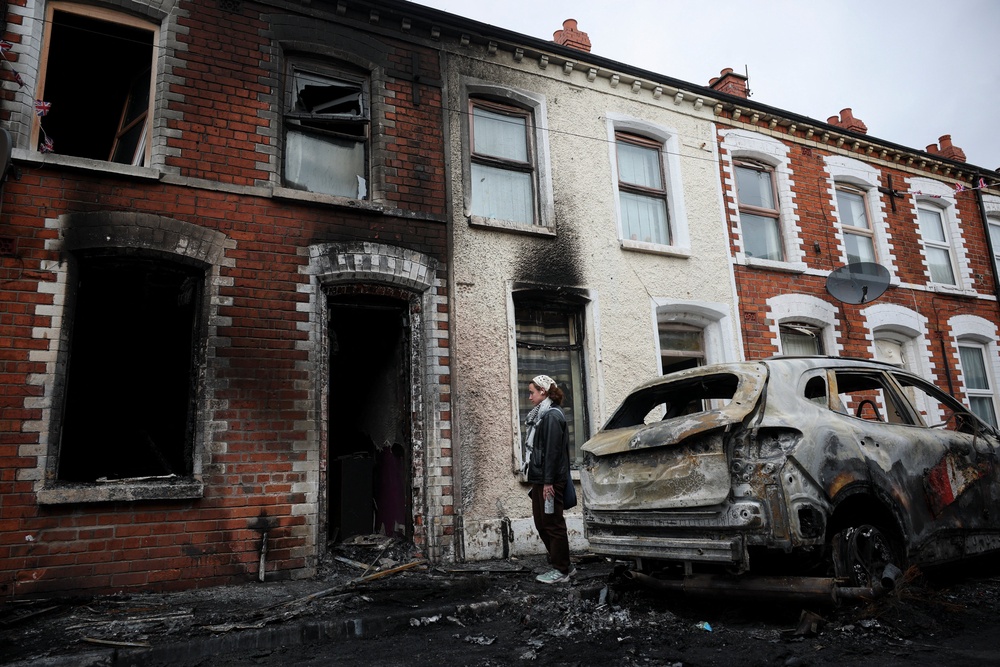 A resident looks at the charred debris scattered on the street in her neighbourhood, in the aftermath of anti-immigrant protests (Reuters)