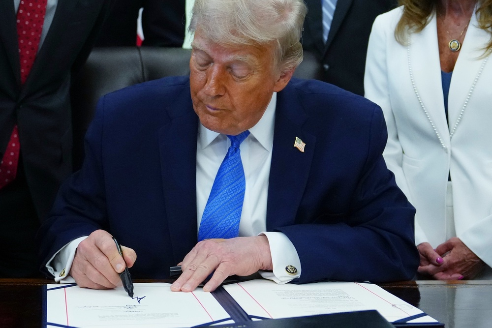 President Donald Trump signs a bill funding immigration enforcement after initially forgetting to sign and dismissing reporters (AP)