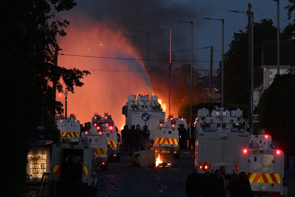 Police water canons spray water as fire burns during protests taking place near the Chimney Corner Hotel (Getty)