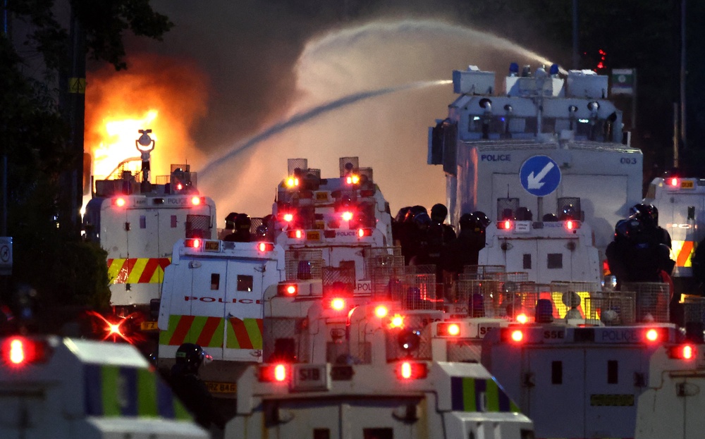 Police use a water cannon as they block the road from protesters (behind) leading to a hotel previously believed to house migrants, on Antrim Road (AFP/Getty)