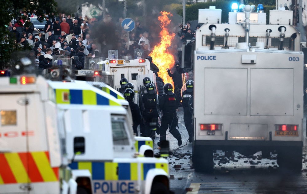 Protestors throw things at Police blocking them from a road leading to a hotel previously believed to house migrants, in Glengormley (AFP/Getty)