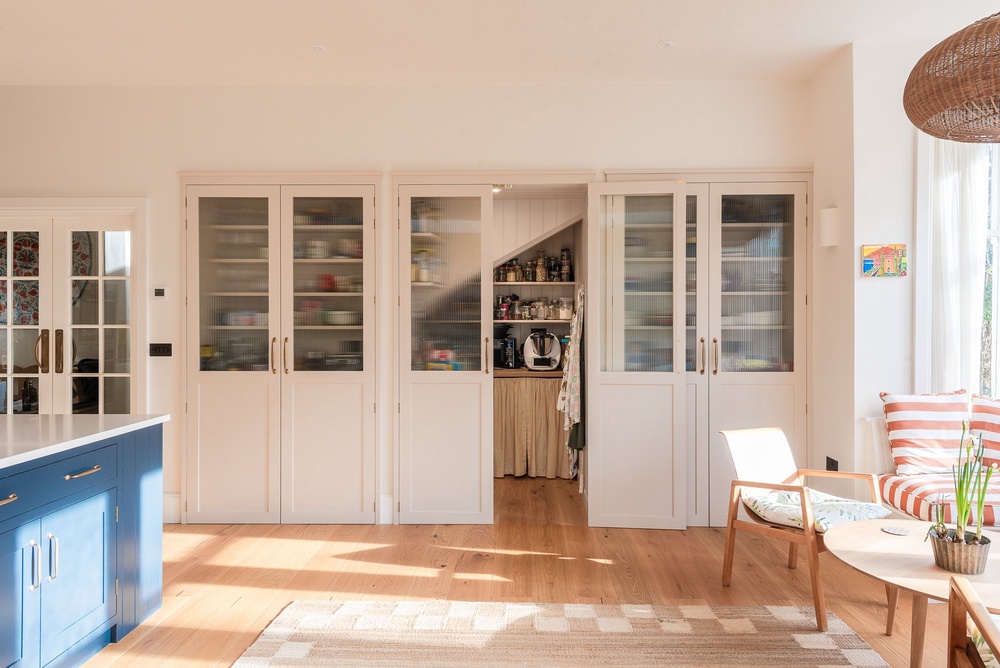 A walk-in pantry and breakfast station sit neatly behind a wall of cabinetry, showing how smart storage can help every inch of a kitchen work harder (Herringbone Kitchens/PA)