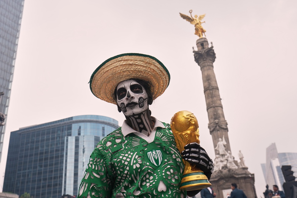 A dancer holds a replica of the World Cup trophy as soccer fans stand along Reforma Avenue in Mexico City (Copyright 2026 The Associated Press. All rights reserved)