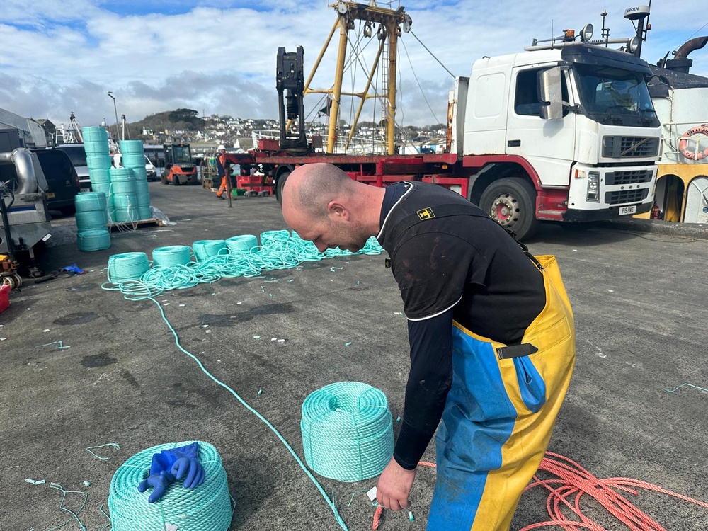 A member of Carroll’s crew repairs the rope they use for crab pots (The Independent)