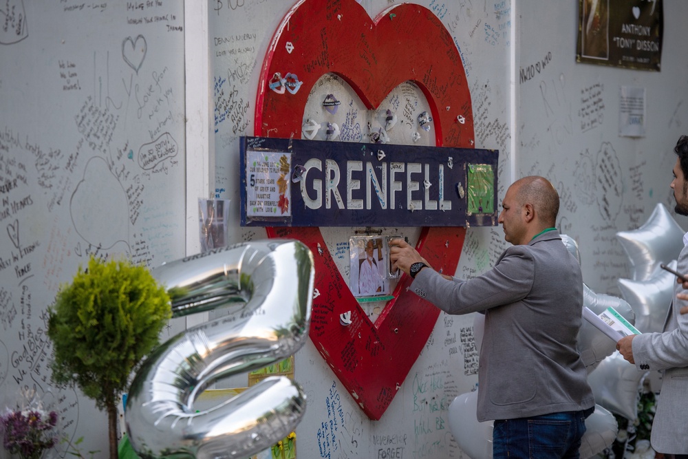 Hamid Ali Jafari staples to a tribute wall at Grenfell Tower a photo of his father, Ali Yawar Jafari, in 2022 (Getty)