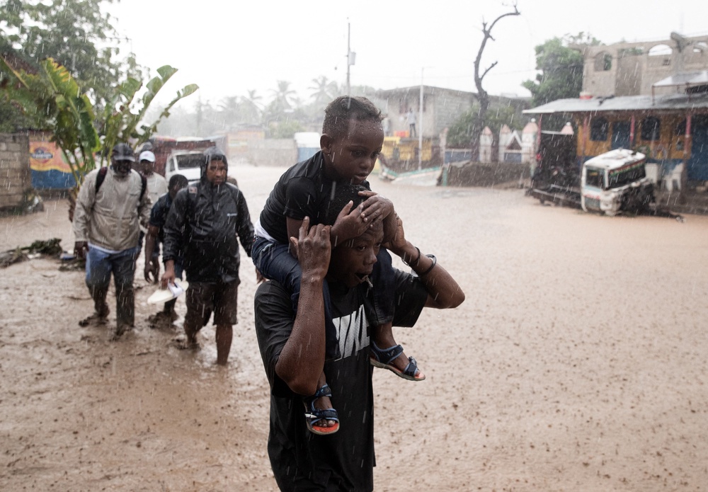 People walk through a flooded street following Hurricane Melissa in Petit-Goave, Haiti, last October. The storm was tied for the strongest Atlantic hurricane on record (AFP via Getty Images)