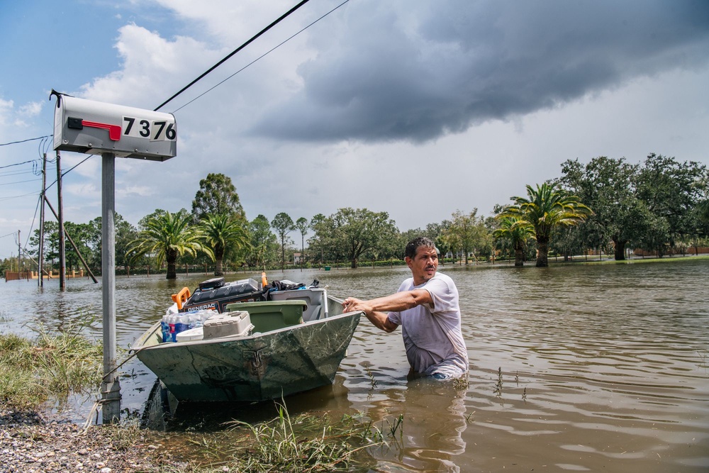 A man pulls a boat through a flooded neighborhood following Hurricane Ida in Barataria, Louisiana, in August 2021. AI models rely on years of past weather data to help produce forecasts (Getty)
