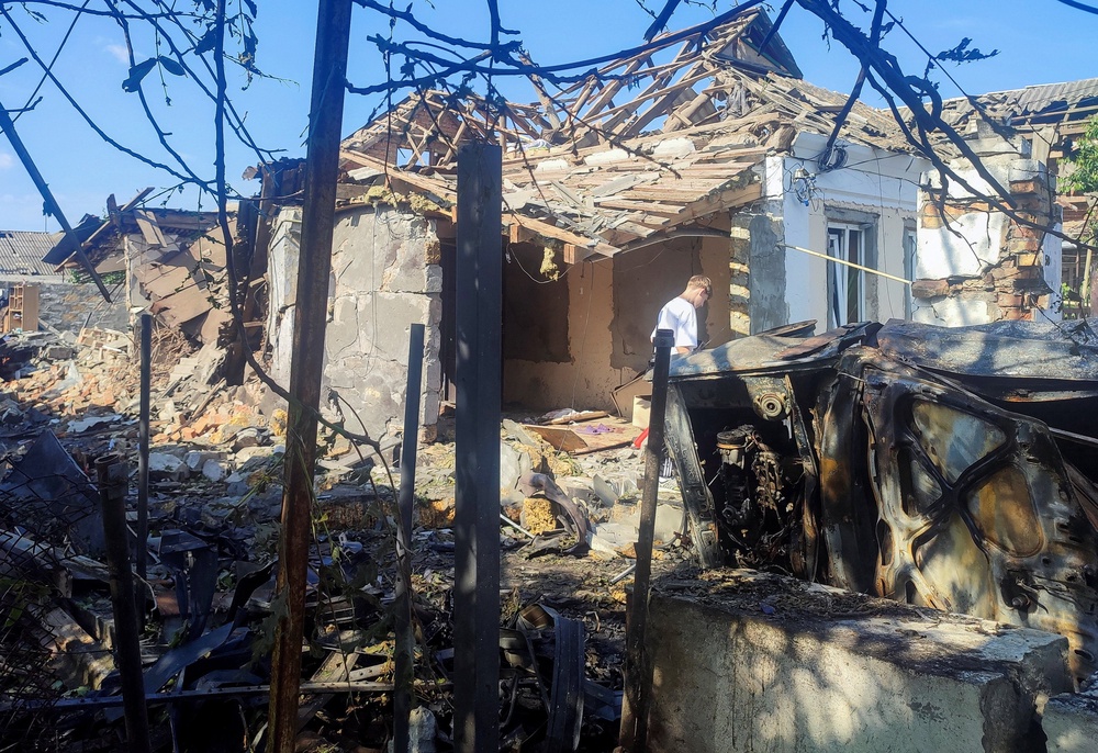 A resident stands at a site where a house was heavily damaged by a Russian drone strike (Reuters)