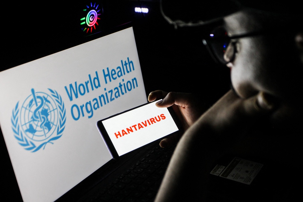 Close up image of a person holding a smartphone displaying the word HANTAVIRUS in front of a computer screen showing the World Health Organization logo in Tunis (AFP/Getty)