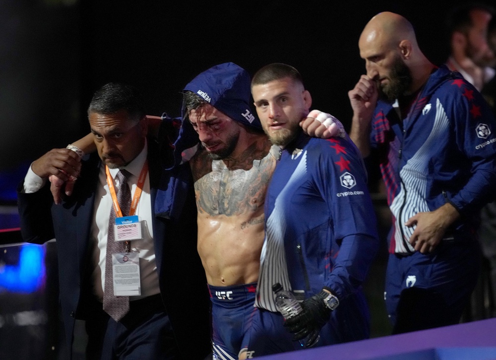 Ilia Topuria (centre) was brutally beaten by Gaethje, retiring on his stool after the fourth round (Getty)
