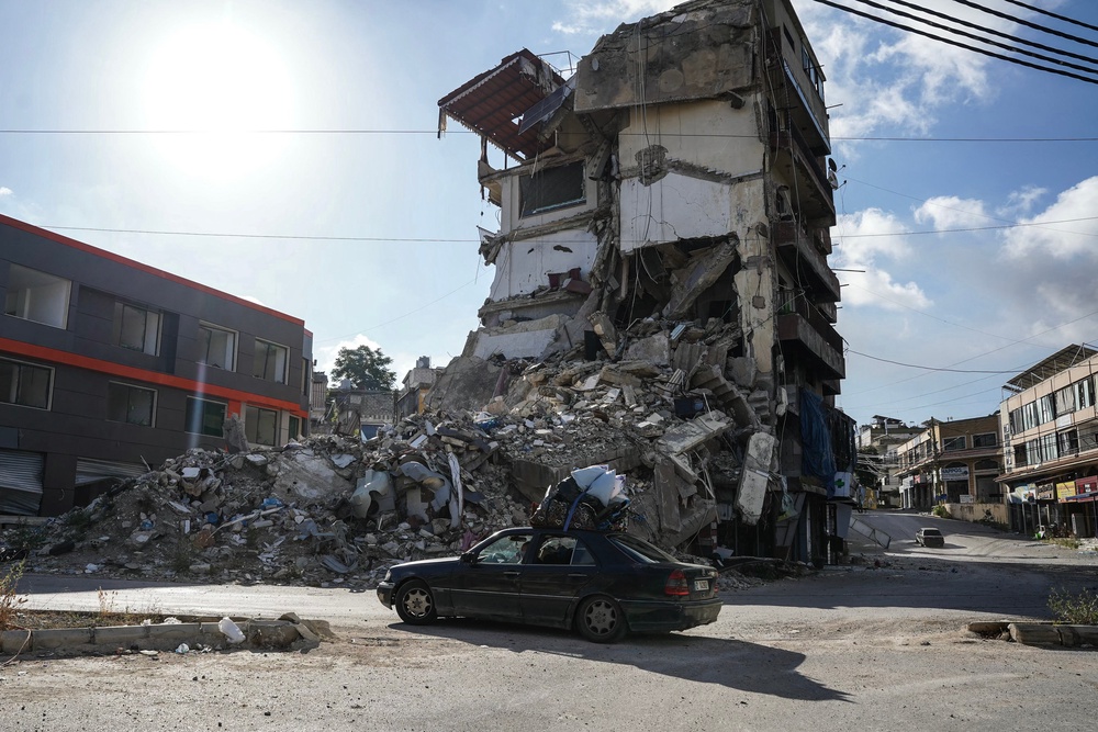 A car loaded with belongings drives past a destroyed building in Nabatieh on June 15 (AFP/Getty)