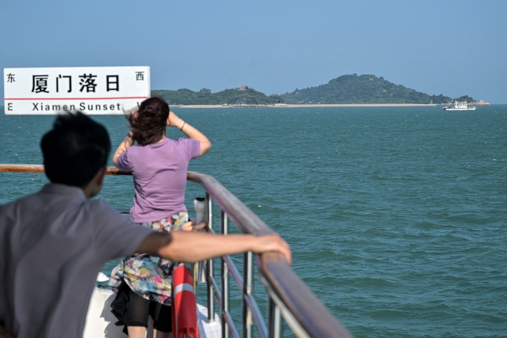 Chinese tourists observe Taiwanese islands during a boat tour across from Taiwan's Kinmen Islands, off Xiamen, in China's southeastern Fujian province on May 25 (AFP via Getty Images)