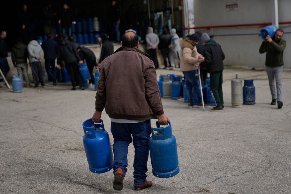 A Palestinian man carries his empty cooking gas cylinders, while he arrives at the main LPG station (AP)