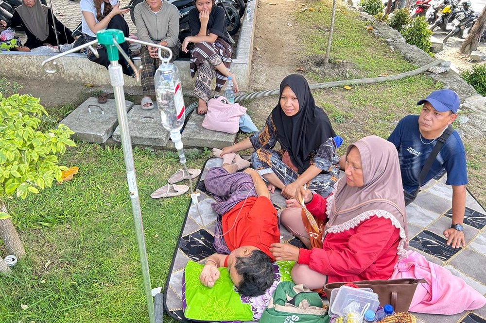 Patients sit outside a hospital following an earthquake in Palu, Indonesia, on 16 June 2026 (AP)