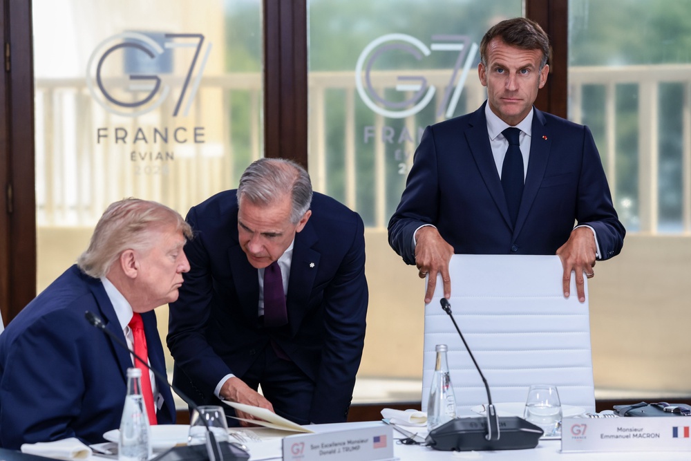 Donald Trump speaks with Canadian Prime Minister Mark Carney next to French President Emmanuel Macron (Getty)
