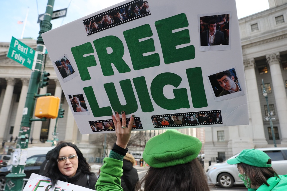Fans of Luigi Mangione attend his pretrial hearings wearing Luigi merchandise and holding supportive signs outside of the courthouse (Getty)