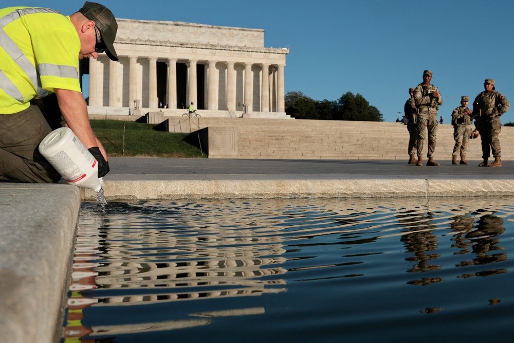 This week, workers were seen dumping hydrogen peroxide into the Reflecting Pool and wading into the water to sccop up algae blooms (Reuters)