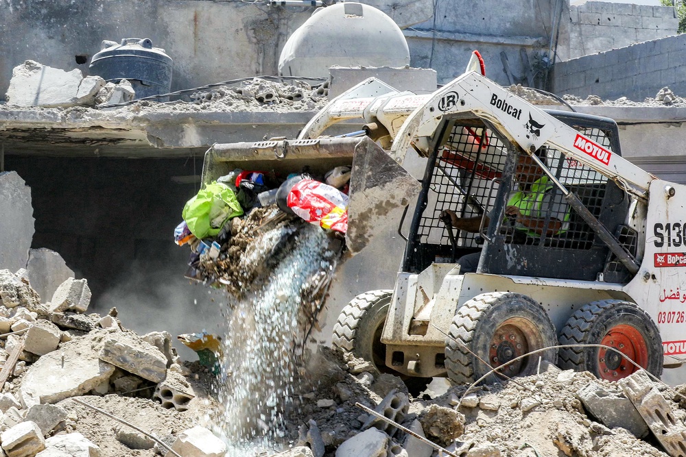 A worker pilots a small excavator to remove the rubble of a destroyed building in the village of Deir Qanoun al-Nahr in southern Lebanon on June 16 (AFP/Getty)