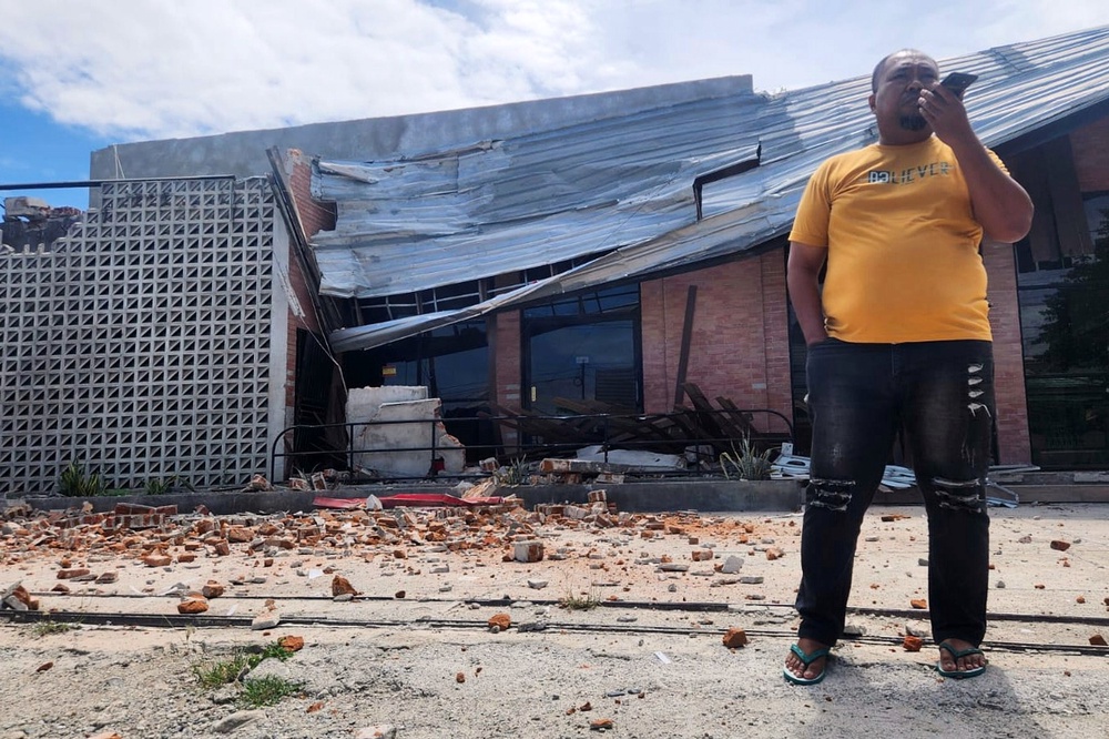 A man talks on his phone near a building damaged in an earthquake in Palu, Indonesia, on 16 June 2026 (AP)