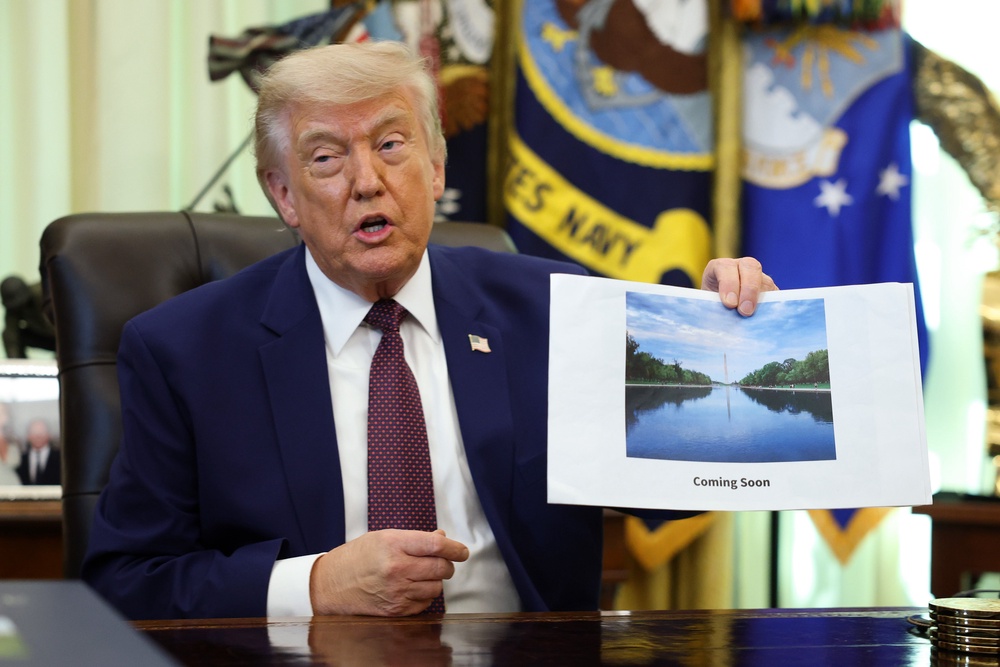 President Donald Trump holds a photo of the Lincoln Memorial Reflecting Pool with the caption, 'coming soon.' After the algae was spotted last week, crews deployed hydrogen peroxide and ‘high-tech nanobubble ozone technology’ to clean the pool (Getty Images)