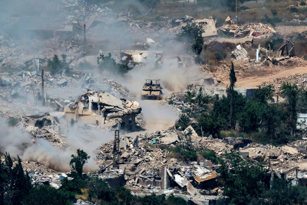 Israeli Merkava tanks driving along a road past destroyed buildings in southern Lebanon on Wednesday 17 June (AFP/Getty)