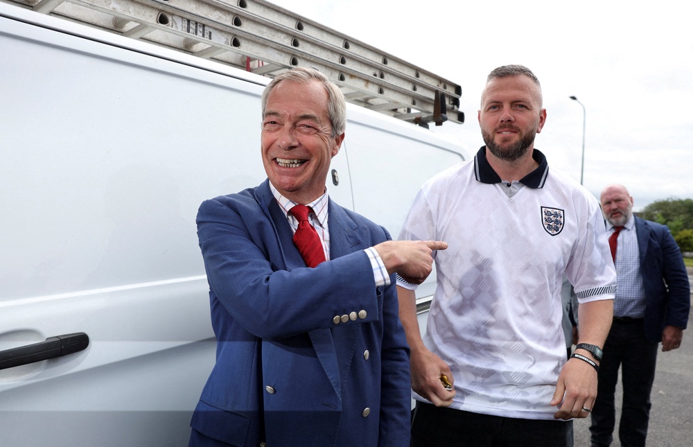 Reform UK leader Nigel Farage reacts next to Reform UK by-election candidate Rob Kenyon as they arrive during the Makerfield by-election (Reuters)