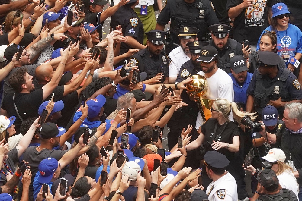 Jalen Brunson carries the trophy alongside fans during the parade (AP Photo/Richard Drew)