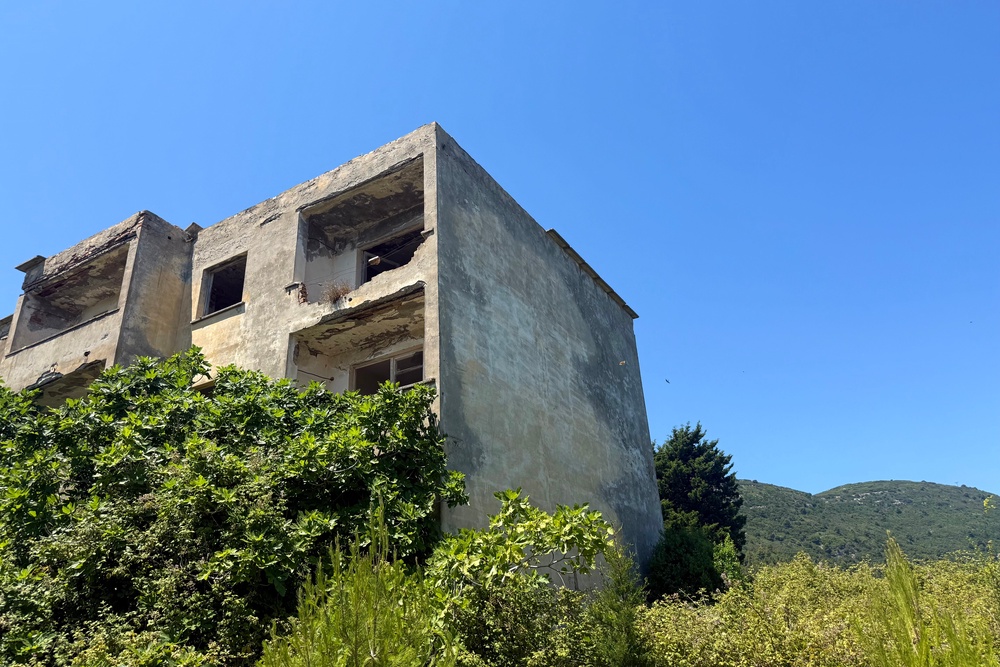 Abandoned buildings line a cracked concrete path that leads into the hills (Annabel Grossman/The Independent)