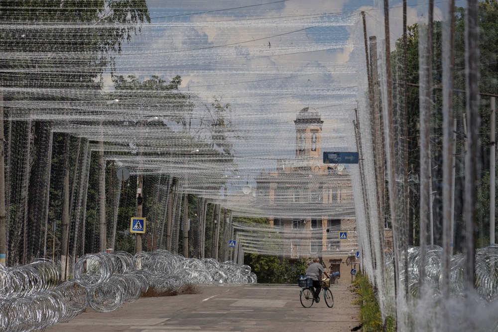 A resident rides a bicycle on a street covered with anti-drone nets in the frontline city of Druzhkivka, amid Russia's attack on Ukraine, in Donetsk region, Ukraine June 19, 2026. (Reuters)