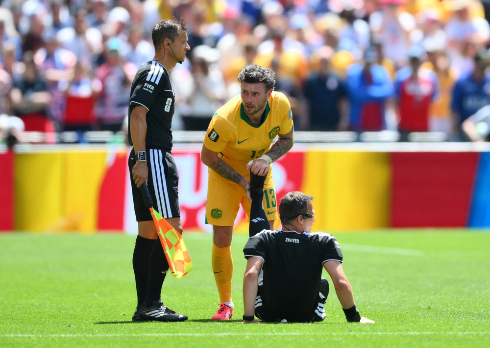 Australia's Aiden O'Neill helps referee Felix Zwayer after suffering cramp (Reuters)