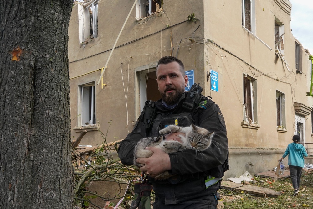 A policeman rescues a cat during search and rescue works in the damaged residential building following Russia's missile attack in Kharkiv (AP)