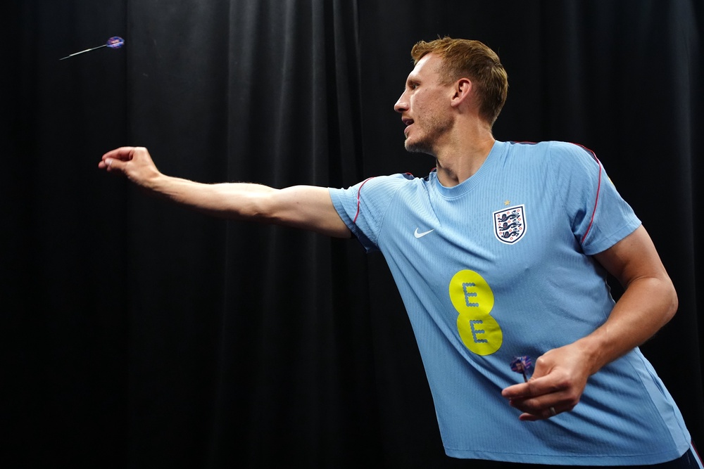 England's Dan Burn plays darts during a press conference (PA)