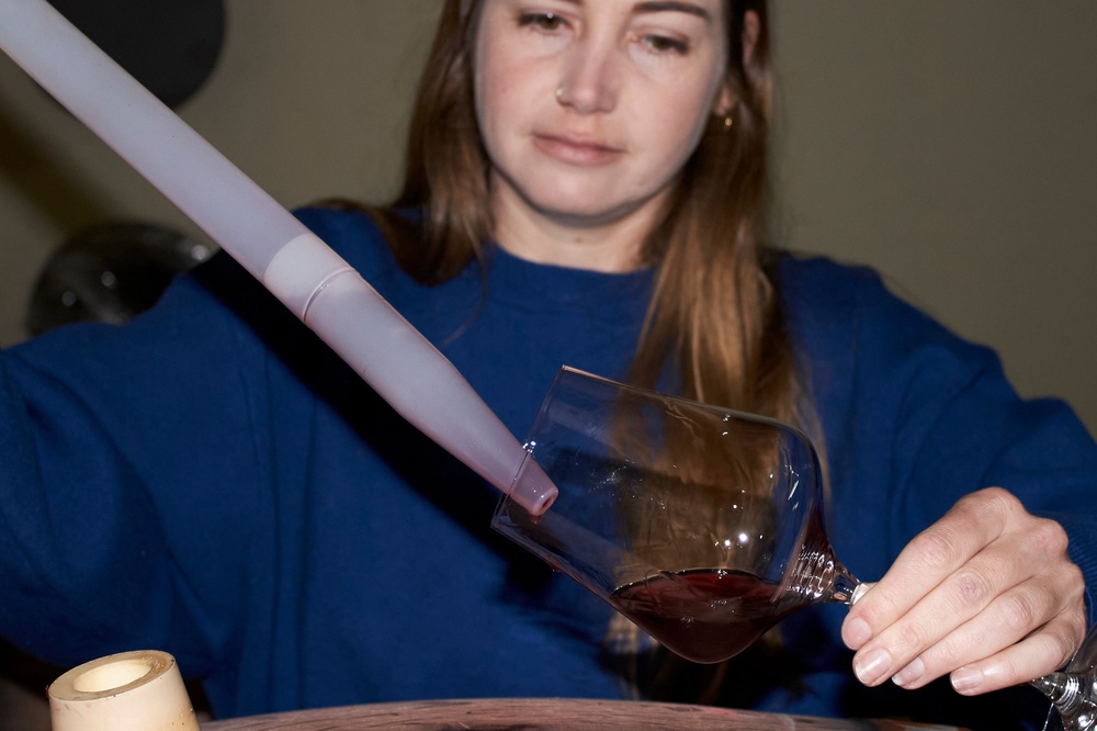 Natasha Jacka pours wine from an oak barrel into a glass using a 
