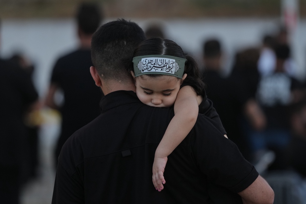 A girl wearing an Ashoura headband rests on her father's shoulder in the southern port city of Tyre, Lebanon. (Copyright 2026 The Associated Press. All rights reserved)