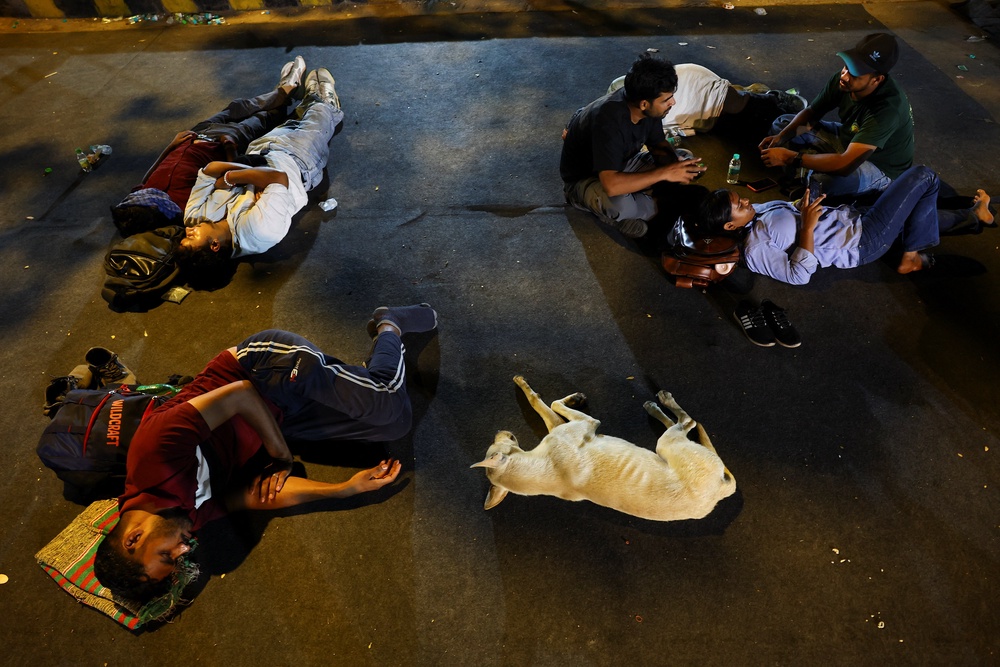 Supporters of the CJP sleep on a carpet laid on the road after spending the night at a New Delhi protest site (Reuters)