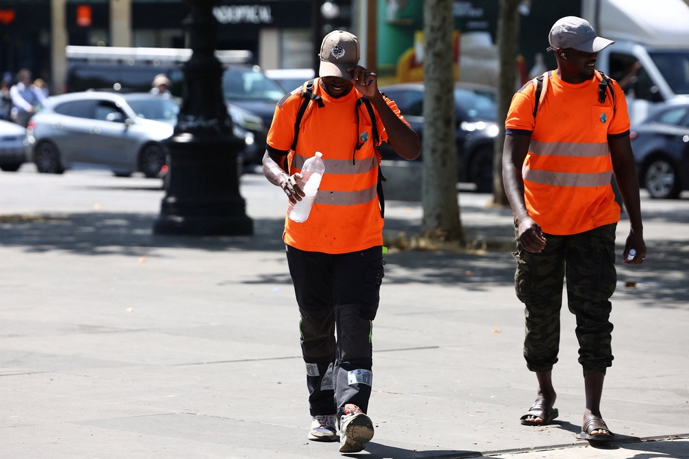 Workers hold bottles of water as they walk past a construction site in Paris (Reuters)